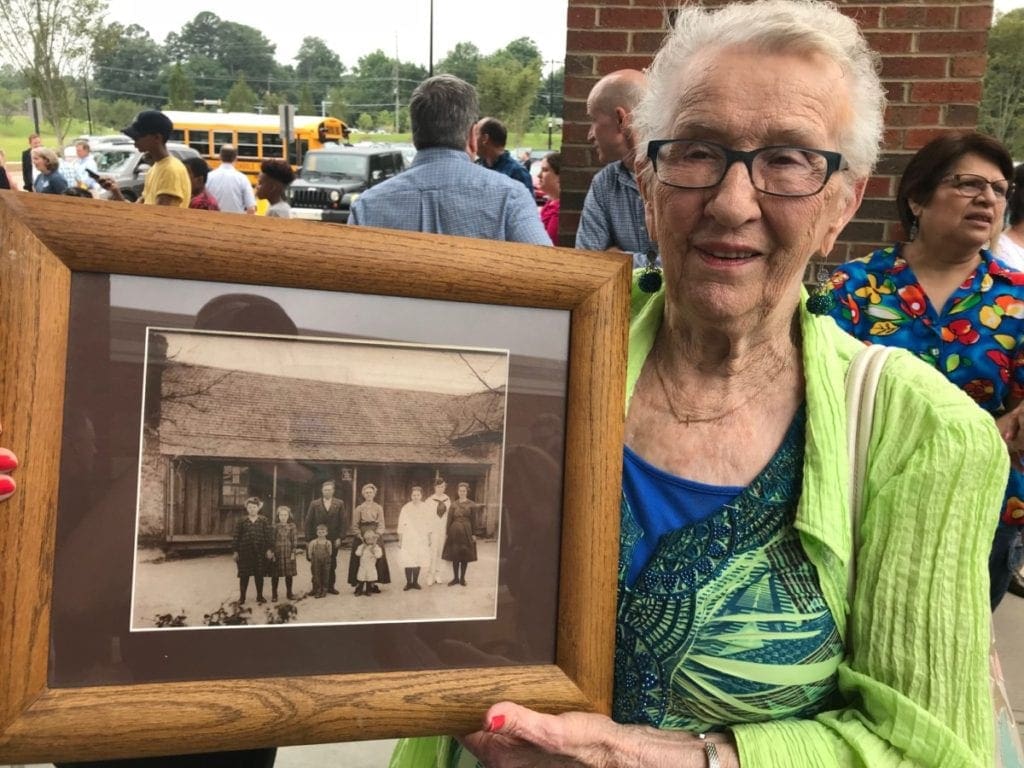 Hill family member Beverly Graham displays a picture of the family and original homestead. Her father is the young boy (center) in overalls. (photo by Rebecca Gaunt)