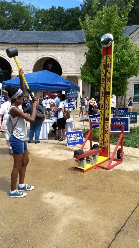 Child draws back hammer in test of strength at carnival in Kennesaw