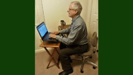 Larry Johnson, the editor and publisher of the Cobb County Courier seated in an office chair in front of a small table with a laptop in article about Cobb County Courier Meet the Editor