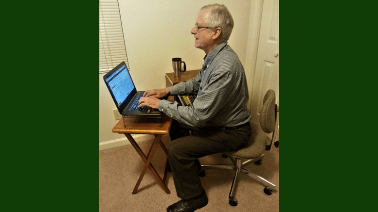 Larry Johnson, the editor and publisher of the Cobb County Courier seated in an office chair in front of a small table with a laptop in article about Cobb County Courier Meet the Editor