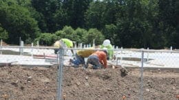 Riverview Landing construction crew at work, crouched over a concrete slab with pipes and conduit