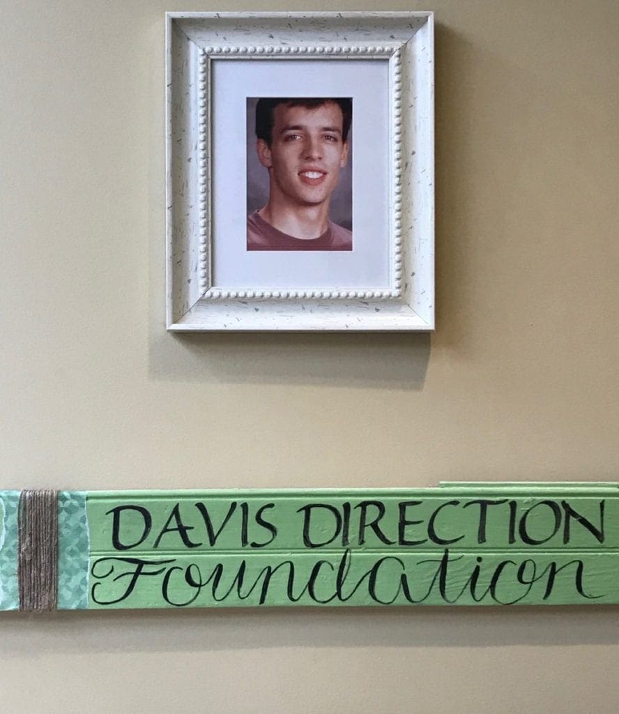 Davis Owen’s photo hangs in the front hall near a wall featuring photos of other lives lost to the opioid/heroin epidemic. (photo by Rebecca Gaunt)