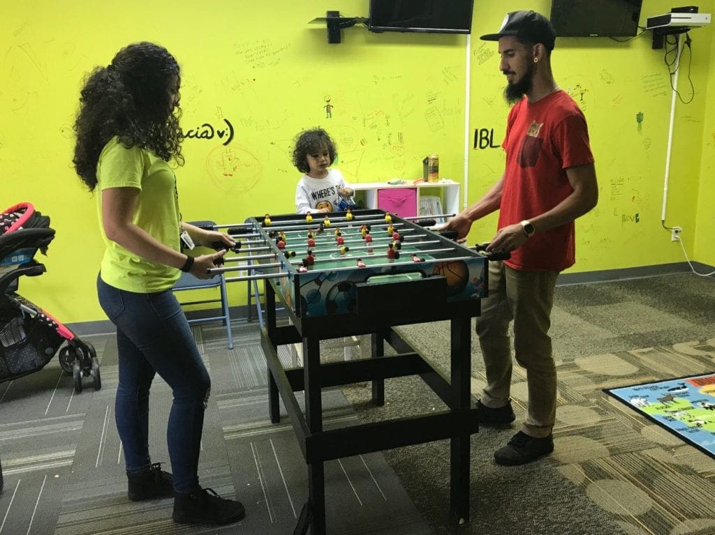 Inspired by Lewis volunteer Celina Gonzalez and Jaymi Rios played foosball while son Julian watched. (photo by Rebecca Gaunt)