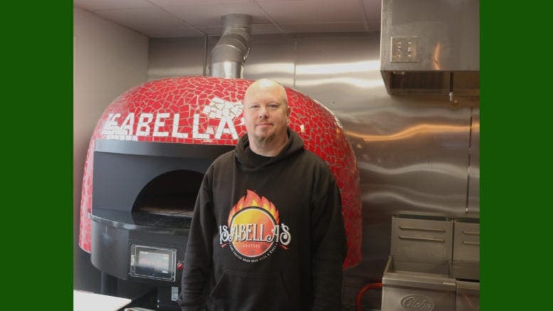 Carlos Bickers, the owner of Isabella's Pizza and Wings in front of his pizza oven (photo by Larry Felton Johnson)
