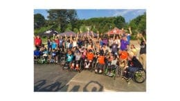 participants in wheelchairs along with supporters at adaptive skateboarding clinic