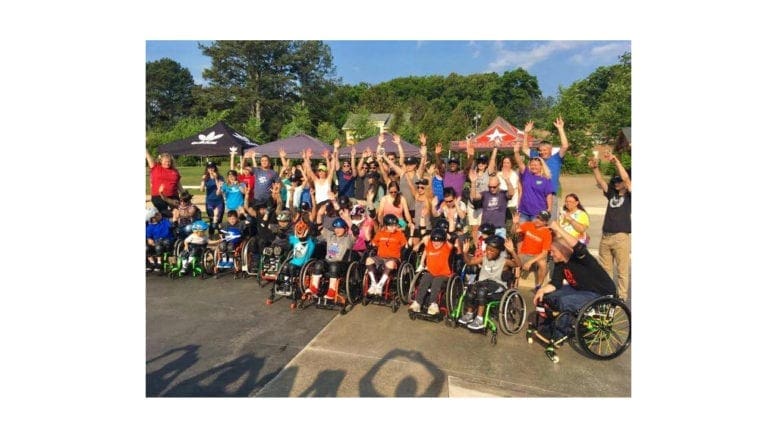 participants in wheelchairs along with supporters at adaptive skateboarding clinic