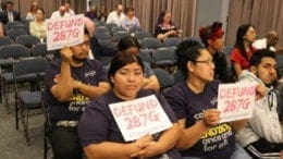 Immigrants rights advocates hold up signs calling for the defunding of 287-G