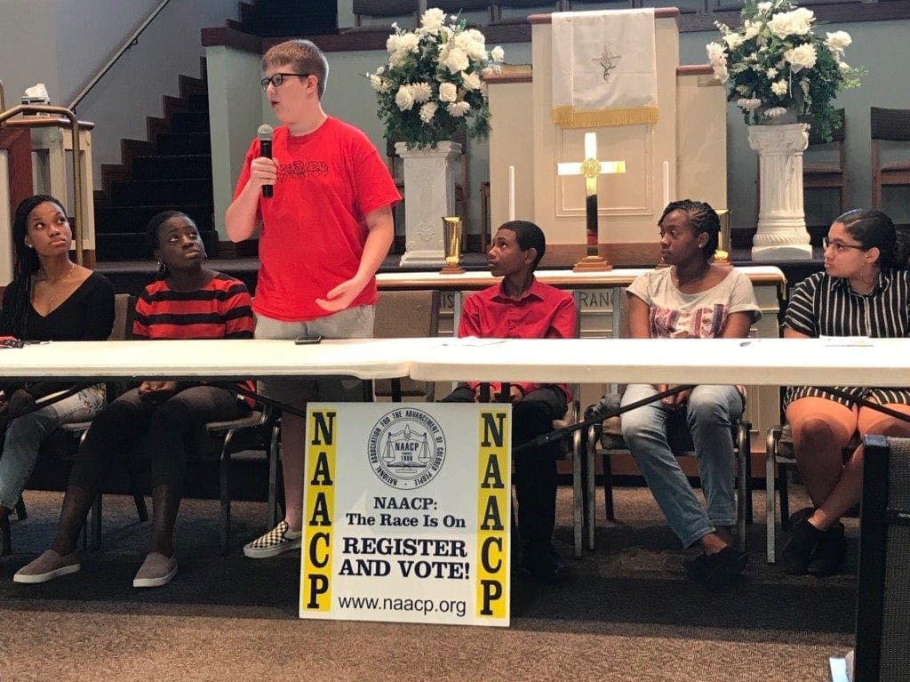 male student in red shirt speaking into microphone