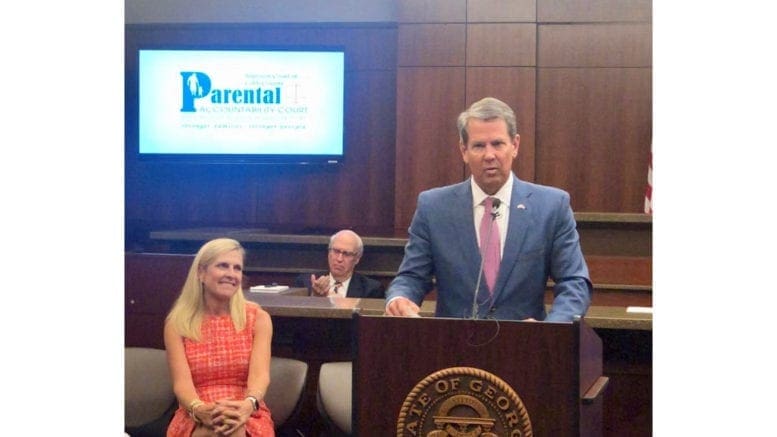 Gov. Brian Kemp, alongside his wiife Marty Kemp, addresses the graduating inaugural class of the Cobb Parental Accountability Court