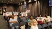 South Cobb residents hold up signs calling for the redevelopment of the long-vacant site of the former Magnolia Crossing apartment complex (photo by Larry Felton Johnson)
