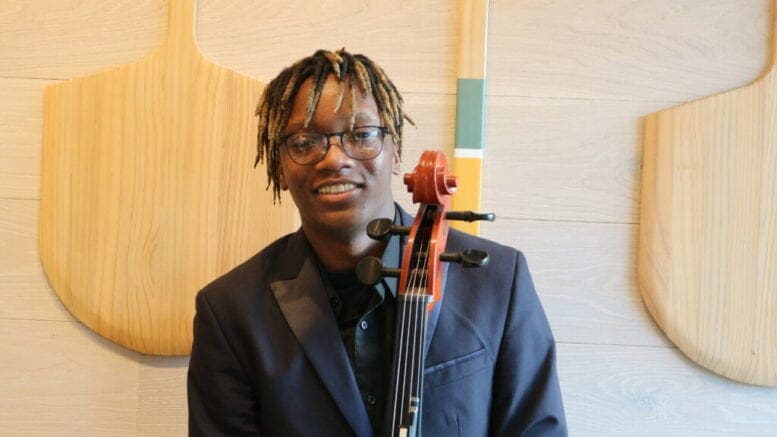 Khalil Payne holding his cello, standing