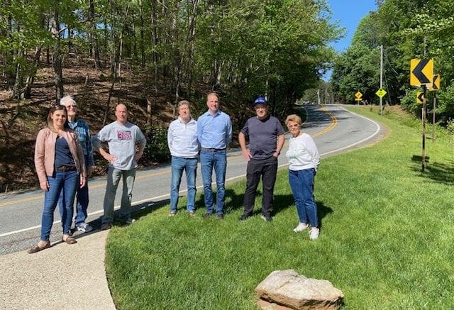 (From l-r) Nikkie Grzelka, John Huey, Ron Gaynor, Michael Thornton, Brad Grzelka, Eugene Williams and Diane Downs hope the most recent accident at this curve will bring much needed safety improvements to Pete Shaw Road.