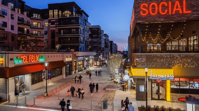 Looking down a street at night in The Battery. Stores and apartments flank the street, which is filled with pedestrians.