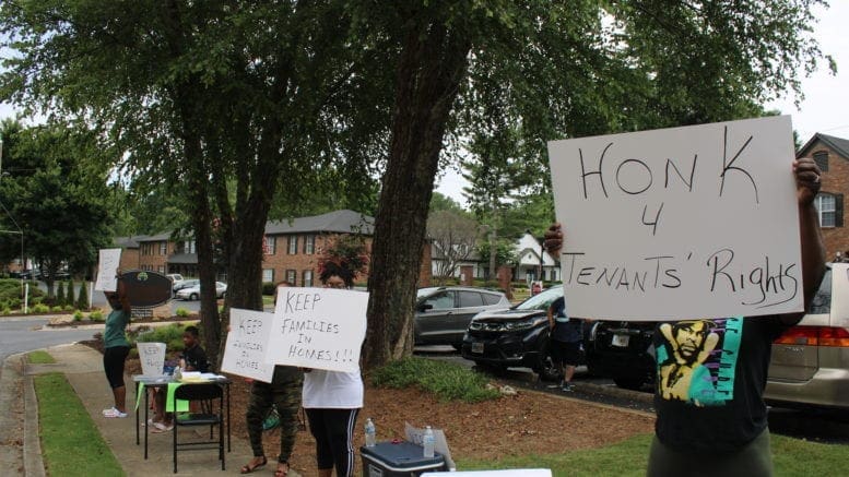 protestors against evictions hold signs in front of apartment complex