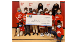 Group of girls dressed in Girls Inc t-shirts holding giant check to advance social and racial equity