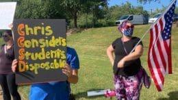 parents outside holding protest signs