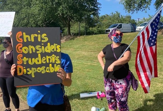 parents outside holding protest signs