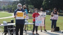 Group of people in front of table holding signs in favor of mask mandate at KSU