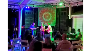 Three musicians on a small stage: mandolin, banjo and guitar