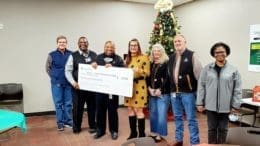 A line of people hold a symbolic donation check