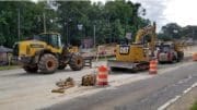 Road construction equipment on shoulder of road with orange safety barriers