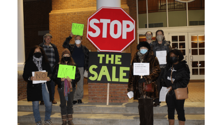 4 men and women outside Smyrna City Hall beside a large sign that says "Stop the Sale"