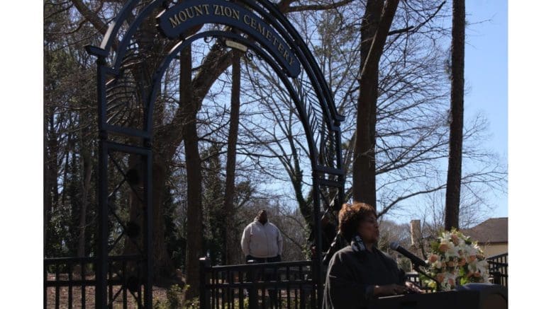 Doreen Smalls at podium with Mt. Zion Cemetery sign in background