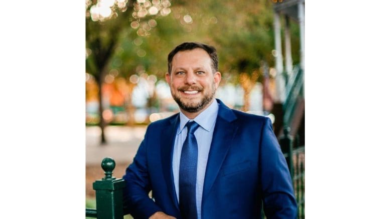 headshot photo of Dustin McCormick in suit with trees in the background