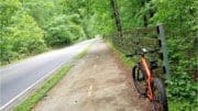 A section of the Mountain to River Trail with trees lining the path and a bicycle in the foreground