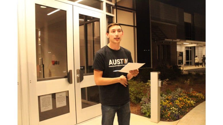 Austin Heller in front of Cobb County School District building reading speech
