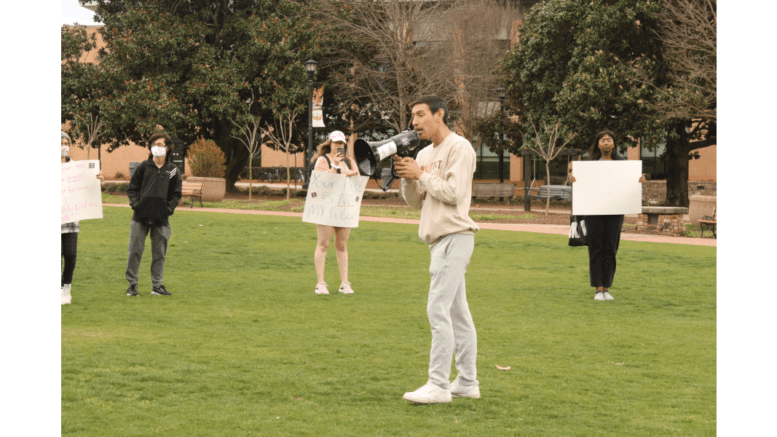 Austin Heller with megaphone in front of students holding signs