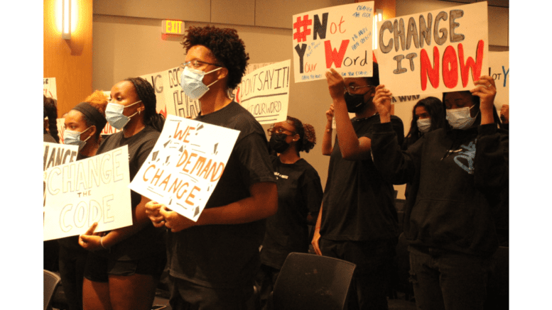 A group of students in medical maks hold signs in protest at the Cobb school board meeting