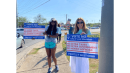 Two women holding up signs opposing Lost Mountain cityhood