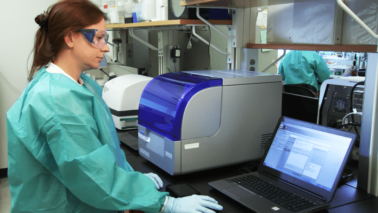 Woman with lab smock looks at laptop monitor in laboratory