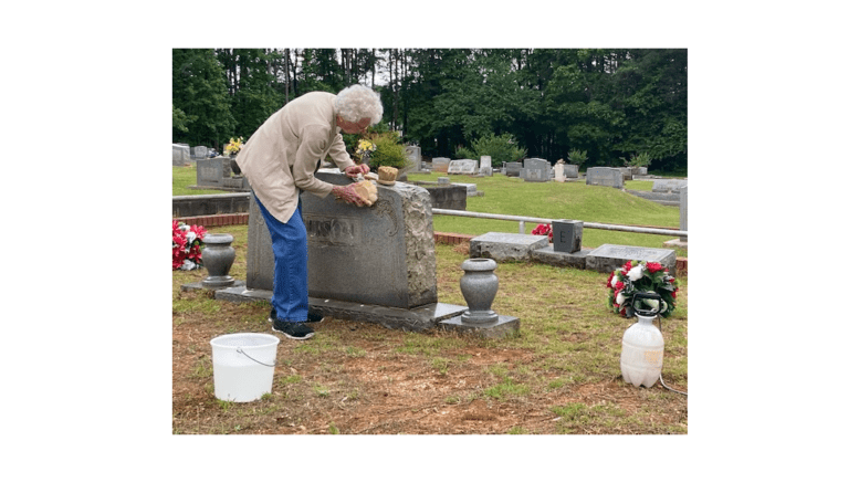 A woman cleans a headstone
