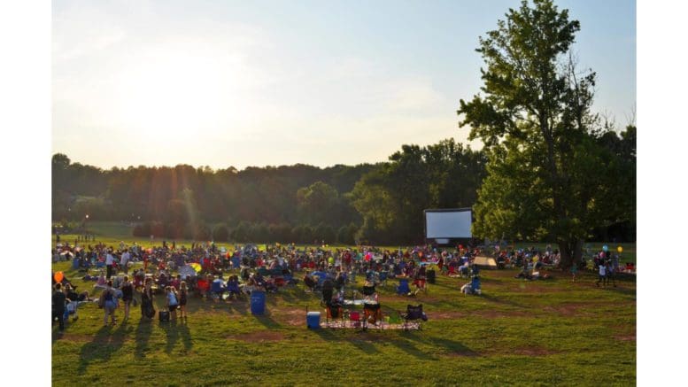 a group of people in a park watching an outdoor movie screen
