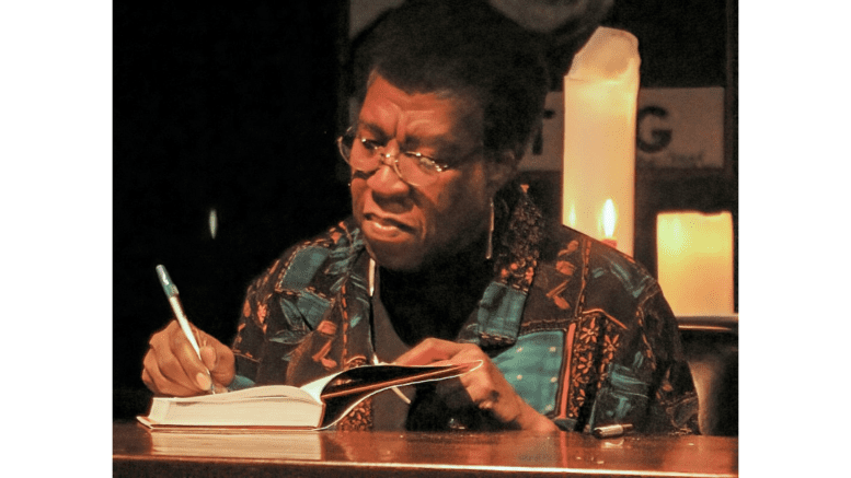 Science fiction author Octavia Butler seated, signing books