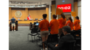 Several audience members in brightly colored shirts stand holding hands at Cobb school board meeting