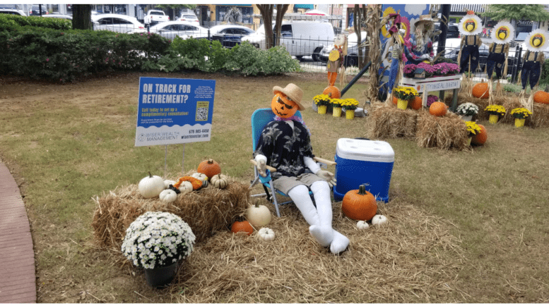 A scarecrow with a pumpkin head in a lawn chair