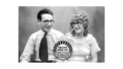 Harold Lloyd and Midred Davis looking at each other lovingly through round-framed black rimmed glasses