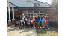 A group of children and adults at a ribbon-cutting