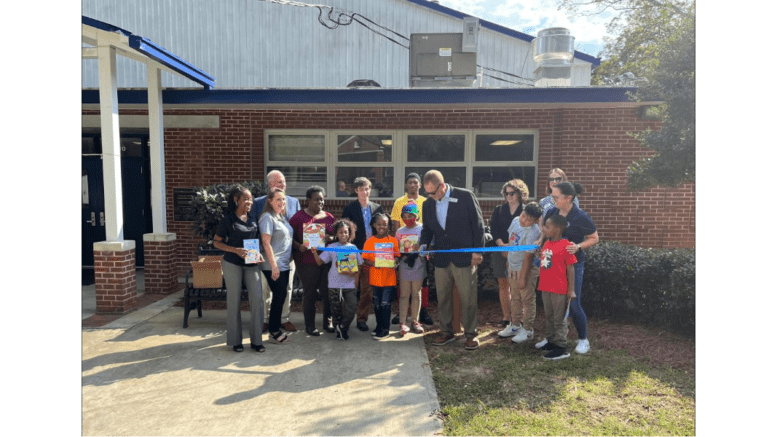 A group of children and adults at a ribbon-cutting