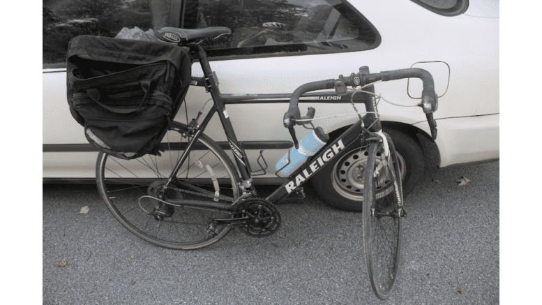 a Raleigh bicycle leaning againt a car