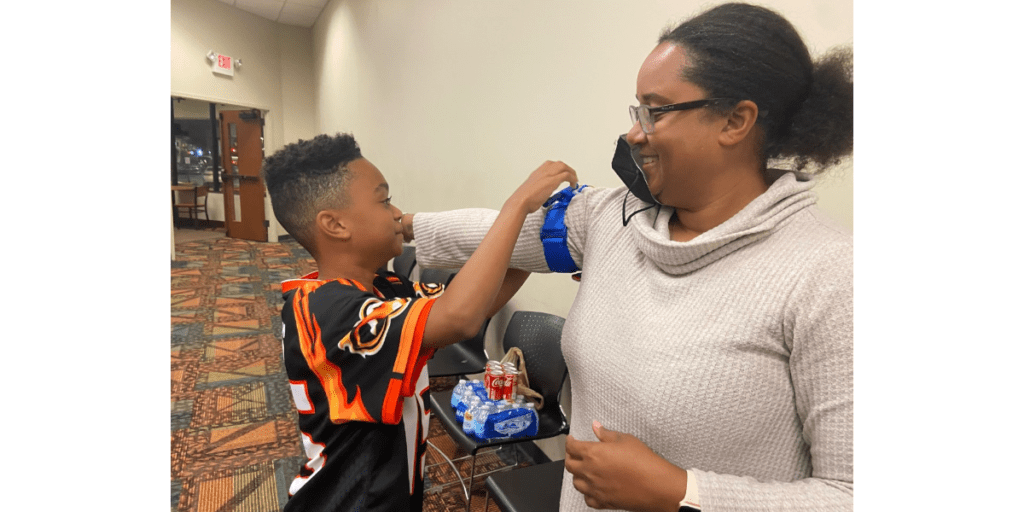 child placing tourniquet on arm of his mother