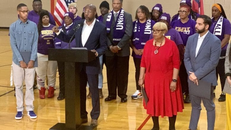 Sen. Raphael Warnock surrounded by supporters at a microphone