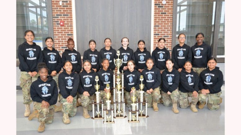 Lady Spartans in two rows behind large trophy