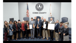 A row of people including Cobb Commissioners and Public Safety officials accepting award certificates from CALEA