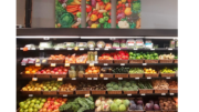 Rows of shelves with colorful vegetables in small brown bins