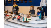 Three children gathered around an electric train set