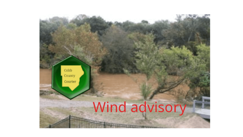 Logos for wind advisory and Cobb County Courier over shot of windblown trees and river